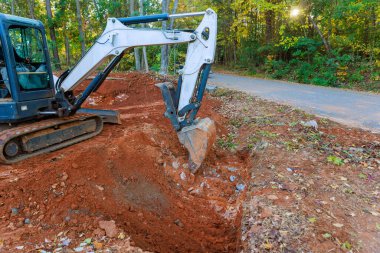 Ağır makineler, kurulmuş drenaj boruları için toprak çukurunu kazıyor