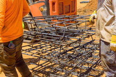 İşçiler inşaat çalışmalarının olduğu gün inşaat alanında büyük inşaat demirleri taşıyorlar.