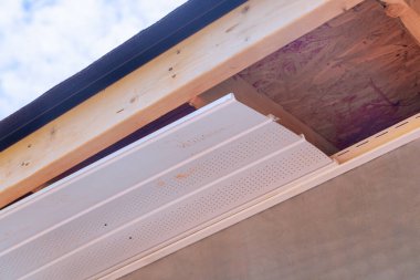 İşçiler yan paneller döşetiyorlar. Ev saçağına plastik çorap malzemesi yapıyorlar.