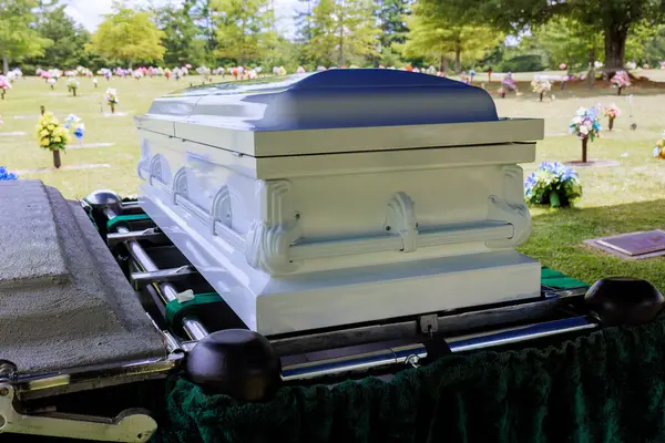Cenaze töreni sırasında mezarlıkta yeşil renkli çiçeklerle dolu bir tabut sergileniyor..