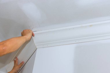 Marangoz dikkatlice dizer, görünüm tasarımını geliştirmek için beyaz odanın köşesine kartonpiyer döşemesi kurar..