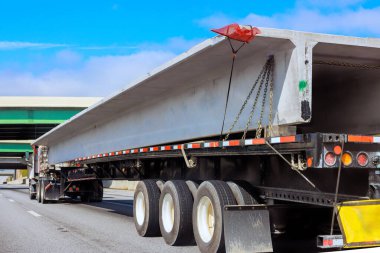 Büyük kamyon inşaat malzemesi taşımacılığı altında yoğun otoyolda beton kiriş taşıyor.