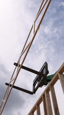 İşçiler, bulutlar yukarıda toplanırken ahşap kirişleri yapım aşamasında yerleştirmek için tele idareciyi kullanıyor..