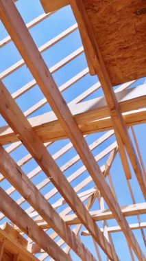 İnşaat sırasında ahşap kirişler ve kirişler, mavi gökyüzüne karşı karmaşık geometrik iskelet ve oryantasyonlu iplik kılıfları gösteriyor..