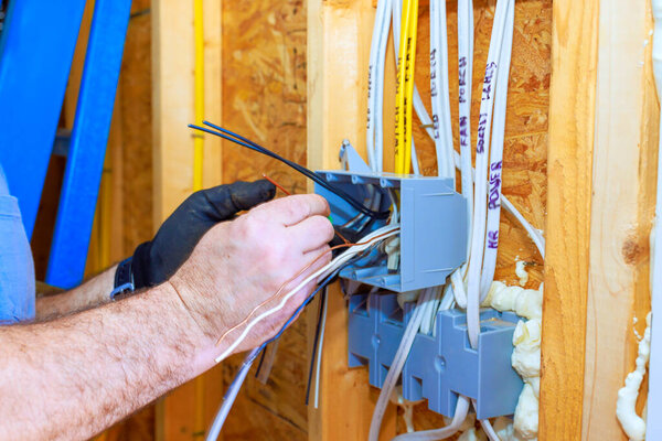An electrician is installing wiring in newly built home, ensuring safe electrical connections for future use.