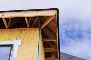 Ahşap çerçeve, arka planda açık mavi gökyüzü olan yeni ev üzerine inşa ediliyor..