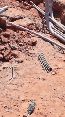 Temelde kumlu zemini şekillendirmek için elektrik boruları döşeyen bir işçi