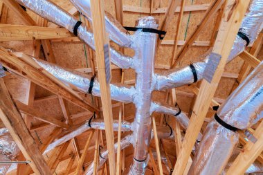 Kanallar, havalandırma sistemi kurulumunu ön plana çıkaran evdeki ahşap kirişlerin arasına yerleştiriliyor..