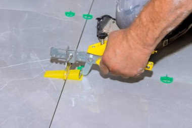 Marangoz ev geliştirme projesinde eşit bir bitiş için seviyelendirme aracı kullanarak fayansları dikkatlice ayarlar.