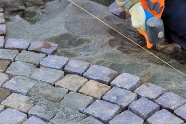 İşçi ustalıkla kaldırım taşlarını yerleştirirken aynı zamanda yeni yol inşaatı için hizalama sağlar