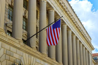Etkileyici bir yapıda, Washington 'da parlak gökyüzüne karşı dalgalanan uzun sütunlar ve bir Amerikan bayrağı sergileniyor.