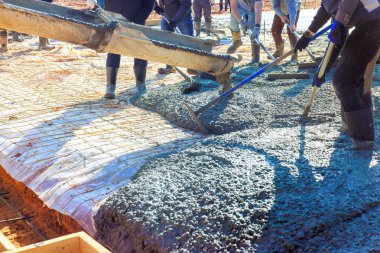 İşçiler inşaat sahasına beton döküyor, temel döşeme üzerine.