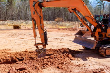 Kazıcı inşaat sahasında çalışıyor. İnşaat alanının çevresini etkin bir şekilde kazıyor. İş gününün altında hendek kazıyor.