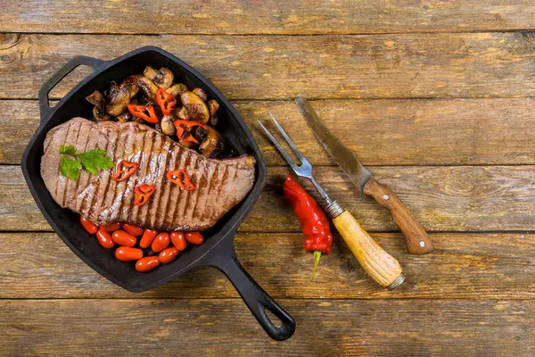 Lezzetli ızgara biftek, mantarlı, kiraz domatesli, dökme demir tavada dizilmiş..