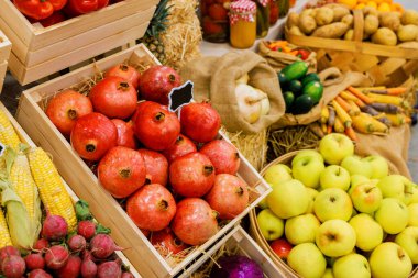 Sonbahar pazarında ahşap sandıklara yerleştirilmiş canlı elma, nar ve sebze seçimi..