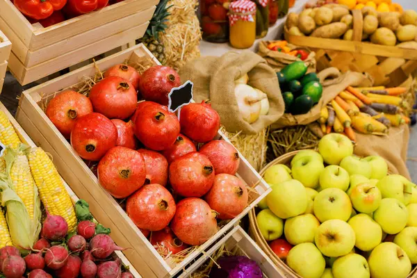 Sonbahar pazarında ahşap sandıklara yerleştirilmiş canlı elma, nar ve sebze seçimi..