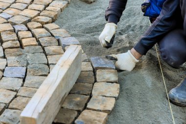 İşçi, iş günü iş yerinde yol inşa ederken kaldırım taşlarını titizlikle yerleştiriyor.