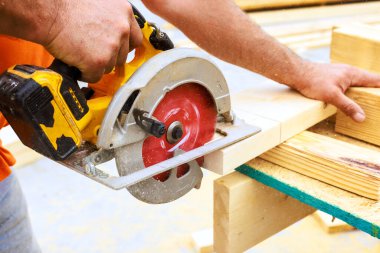 Ustabaşı, çalışma saatleri boyunca inşaat sahasında ahşap tahtalar kesmek için dairesel testere kullanır..