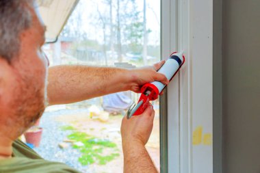 Ev sahibi hava şartlarına karşı yalıtım koruması için pencere çerçevesine kalıntı uygulamaya hazırlanıyor.