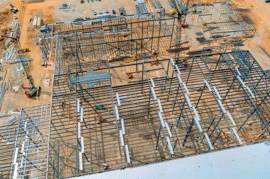 Büyük inşaat sahasında, iş yeri üzerine makine malzemelerinin arasına metal iskelet kuruluyor