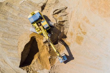 Kazı makinesi inşaat alanında özenle çalışıyor, temel oluşturmak için kumu hareket ettiriyor..