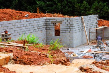 İşçiler, iş günlerinde ağaçlarla çevrili dağlık alanda temele blok kuruyorlar..