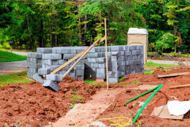 Erkekler, kenar mahallelerde inşaat alanlarıyla çevrili beton bloklar kullanarak taş duvar inşaatında çalışıyorlar.