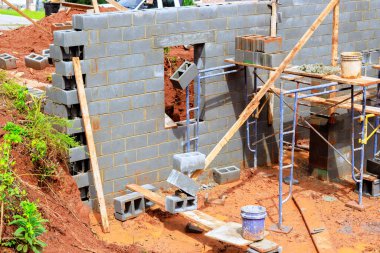 İşçiler yeni yapı için bloklar koyarken, inşaat alanındaki araçlar iş günü boyunca yapı iskelesi kullanılıyor.