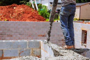 İnşaat alanındaki inşaat duvarına işçiler tarafından beton dökülüyor.