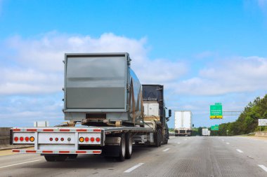 Büyük kamyon, yoğun bir otoyolda, sürüş gününün altında önemli konteynırlar taşıyor.
