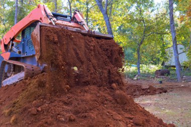Ağır makineler ormanlık alandaki toprağı temizler, gelecekteki peyzaj faaliyetleri için toprağı hazırlar.