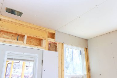 Tamamlanmamış iç yenileme, konut ortamında çerçevelenmiş alçıpan kurulumunu gösteriyor.