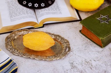 1 Ağustos 2025, Kudüs İsrail, Etrog narenciye, açık dua kitabının kutsal metninde David 'in Yıldızı amblemi. Geleneksel Yahudi bayram simgeleri arasında Sukkot festivali için kippah tallit de yer alıyor