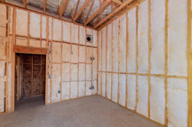 Çıplak çerçeve köpük yalıtımlı tamamlanmamış oda, inşaat sürecinin altını çiziyor yeni ev.