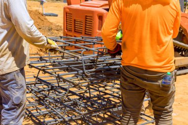 İnşaat işçileri inşaat alanında iş yapmaya hazırlanırken çelik inşaat demiri yığını taşıyorlar.