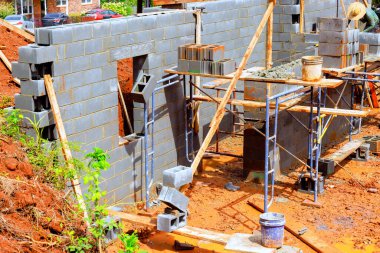 İnşaat işçileri etkin bir şekilde inşaat alanında beton blok duvarı ve çalışma günü altında iskele monte ediyorlar.