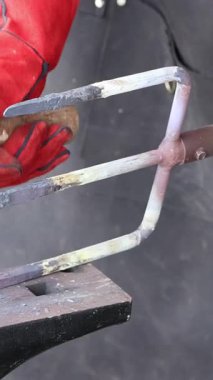 Yetenekli demirci örse sıcak metal çakıyor. Bahçe çatalı yapımı sırasında geleneksel zanaatkarlık sergiliyor.