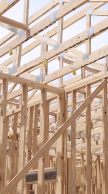 İşçiler parlak mavi gökyüzünün altında kirişlerle ahşap çatı kirişleri inşa ediyorlar..