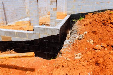 İşçiler yeni evin çimento bloklarını örüyorlar. Duvarları açıkta, etrafı kir içinde..