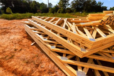 İstiflenmiş ahşap kirişler, inşaat sahasına yerleştirildi. İş günü toprak zemindeki ağaçlarla birlikte..