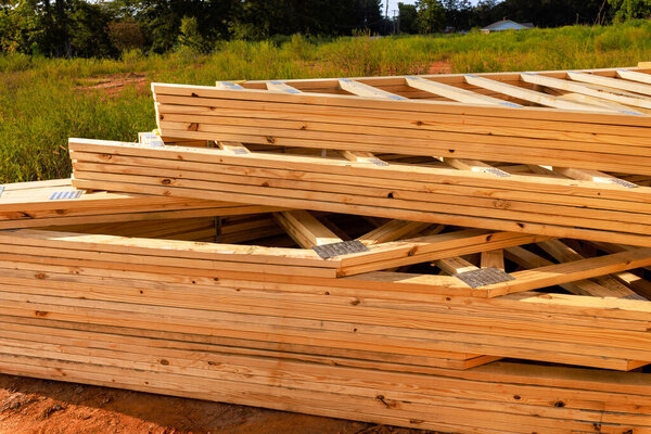 Много деревянных досок кровельных балок аккуратно укладываются на строительной площадке во время выполнения рамочных работ