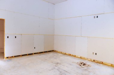 Alçıpan döşenmiş tamamlanmamış bir oda, çıplak duvarlar, temiz beton zemin son rötuşları bekliyor..