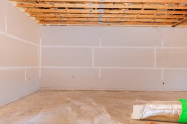 Tamamlanmamış iç mekan, devam eden inşaat yenileme çalışmalarını gösteren, çıplak duvarları ham tavana sahip..