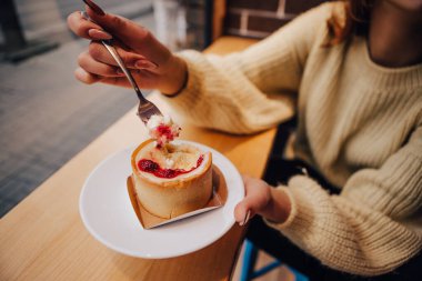 Sıcak kazak giymiş gülümseyen bir kadın, tatlı yemekten hoşlanan, lezzetli bir kek. Sokak kafesinde abur cubur. Yılbaşı süsleri, çelenkler
