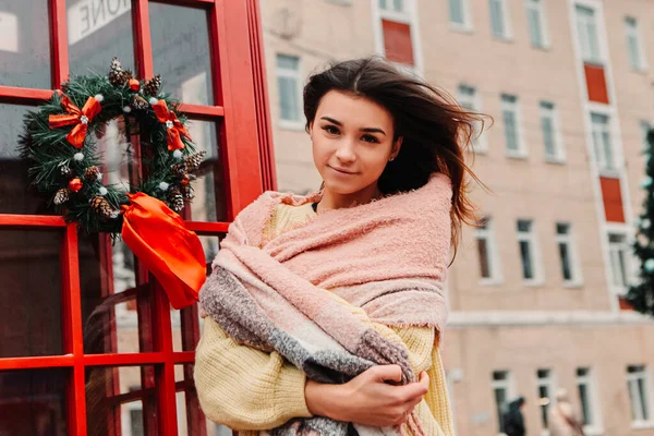 若いかなり笑みを浮かべて女性の暖かいセーターを着て 電話ボックスの近くに立って祝う 冬の市場の休日フェア 旅行精神リゾート 新年のクリスマス飾り — ストック写真