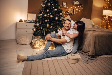 Güzel, genç, romantik bir çift hediyelerini açıyor. Çiçekler ev içinde rahat bir iç atmosfer Noel ağacı süslemeleri kış akşamını kutlayan bir Noel partisi. 