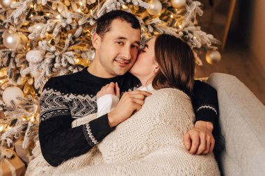 Hoş, genç, romantik bir çift battaniyenin altında yatıyor, çelenkler evde rahat iç atmosfer yılbaşı ağacı süslemeleri kış akşamını kutlayan tatil partileri. 