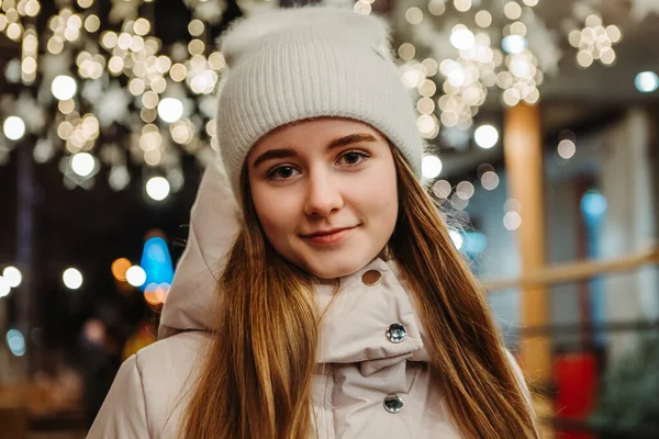 カメラを見て暖かいジャケットを着た若いかなり笑顔の女性の肖像画を閉じます 冬の市場の休日フェア 旅行精神リゾート 新年のクリスマスの装飾 ガーランド — ストック写真