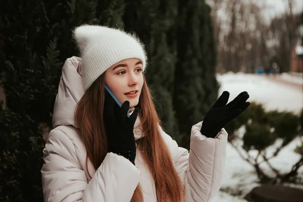 若いかわいい女性は クリスマスツリーの近くに立って 携帯電話のジェスチャーを話して 暖かいジャケットを着て祝う 冬の休日 旅行精神リゾート 新年のクリスマス飾り — ストック写真