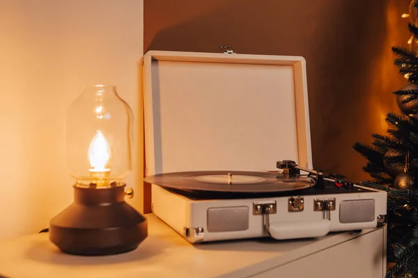 Cozy atmosphere image of vinyl vintage turntable record player and desk lamp with warm light on table